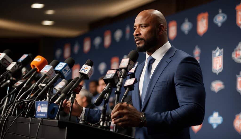 A former NFL player speaking at a press conference, surrounded by cameras and microphones, with a backdrop of logos from various media outlets